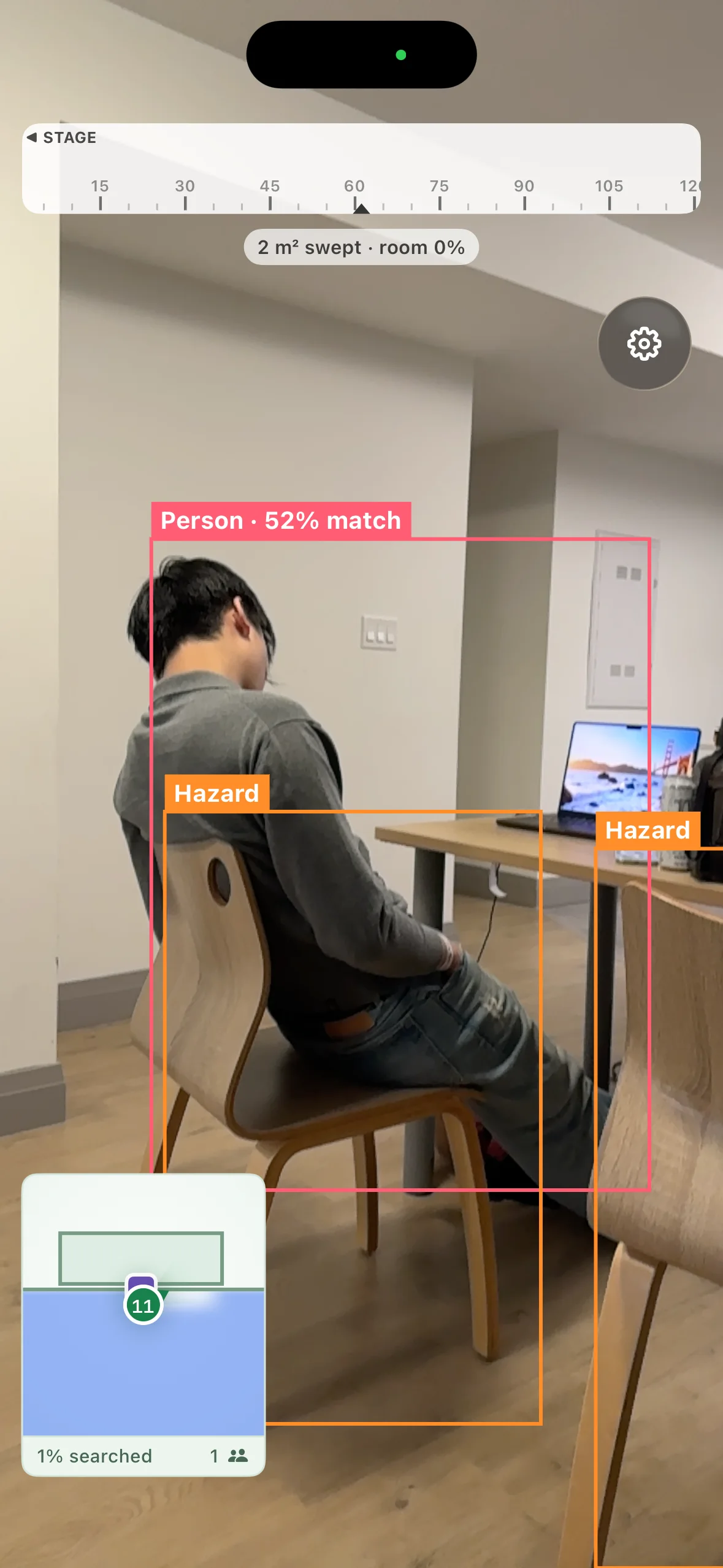Beacon phone view mid-search: a heading strip pointing towards the stage, a Person 52% match box drawn around someone at a desk, two hazard boxes, and a minimap showing 1% searched